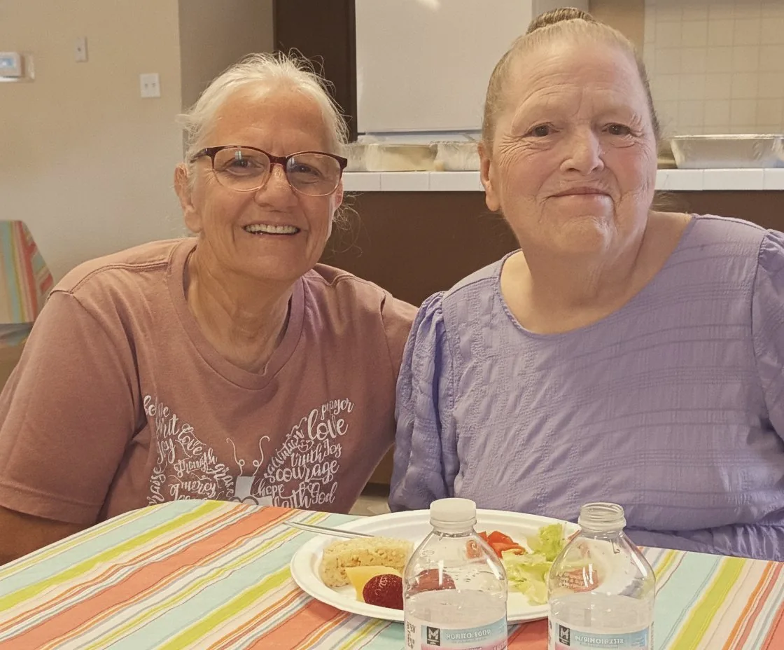 Two friends sharing lunch and a laugh at a church potluck